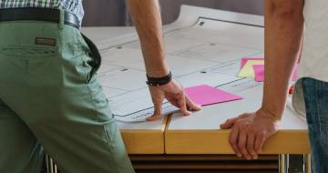 man staat voor tafel met post-its