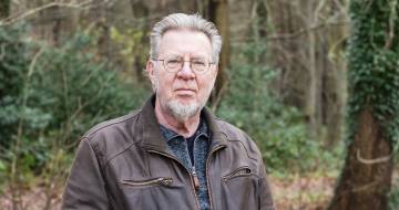 peter siebesma staat buiten in een herfstbos en kijkt in de camera