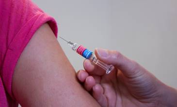 ontblote bovenarm met spuit voor vaccinatie