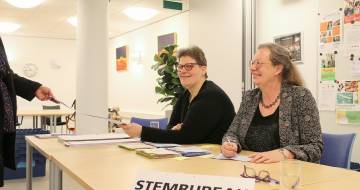 twee vrouwen achter een bureau waar stembrueau op staat