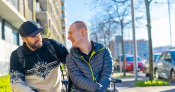 Man in een rolstoel met begeleider