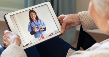 Oudere mevrouw die via haar tablet beeldzorg ontvangt van een zorgprofessional