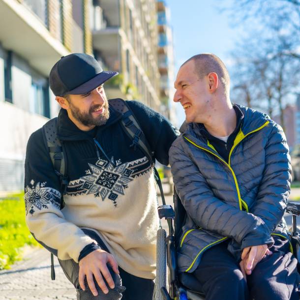 Man in een rolstoel met begeleider