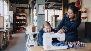 vrouw lachend achter de naaimachine