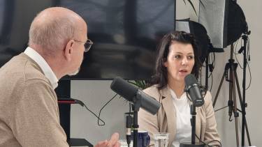 Een man en een vrouw zitten achter twee microfoons aan tafel