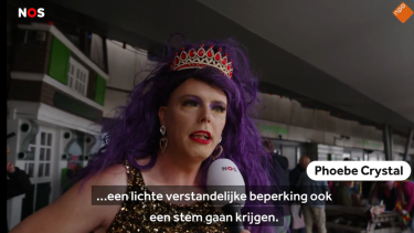 Vrouw met groot paars kapsel en kroon op voor de camera van NOS